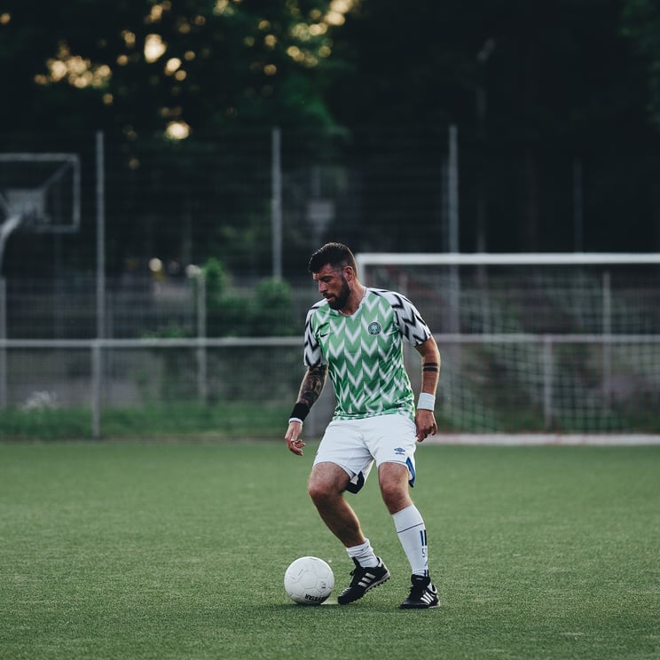 A Man in Printed Shirt and White Short Playing Soccer on the Field